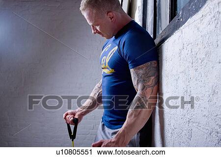Stock Image - Young man using resistance band. Fotosearch