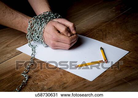 "Young man with chains wrapped around his wrists, paper and broken pencil in front of him, focus on hands" View Large Photo Image Stock Image - "Young man with chains wrapped around his wrists, paper and broken pencil in front of him, focus on hands". Fotosearch