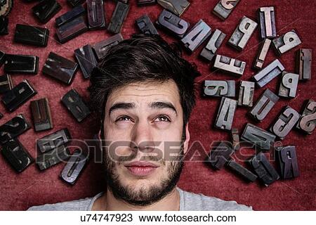 Young man with letterpress letters surrounding his head View Large Photo Image Stock Image - Young man with letterpress letters surrounding his head. Fotosearch