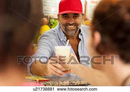 Stock Image - "Young tourist couple buying smoothie in juice bar, Copacabana town, Rio De Janeiro, Brazil". Fotosearch