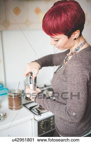 Stock Image - Young woman at home making coffee. Fotosearch