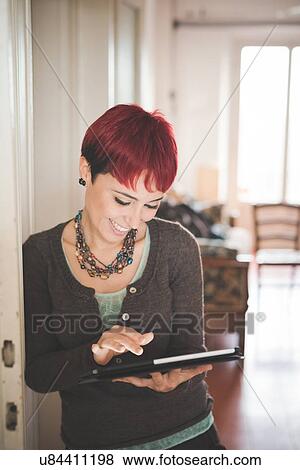 Stock Photo - Young woman at home using digital tablet. Fotosearch