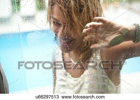 Stock Image - "Young woman behind window of hotel swimming pool, Rio De Janeiro, Brazil". Fotosearch