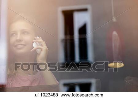 Young woman chatting on smartphone at cafe window View Large Photo Image Stock Photo - Young woman chatting on smartphone at cafe window. Fotosearch