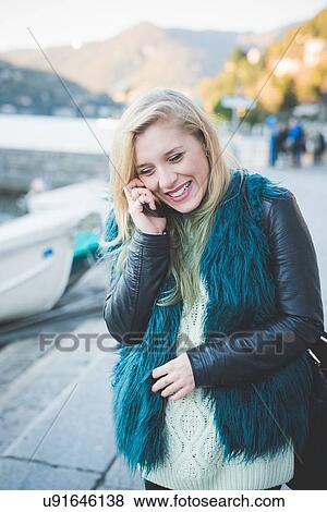 Stock Photo - "Young woman chatting on smartphone at Lake Como, Como, Italy". Fotosearch