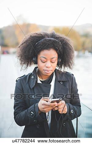 "Young woman choosing music for headphones on lakeside, Como, Italy" View Large Photo Image Picture - "Young woman choosing music for headphones on lakeside, Como, Italy". Fotosearch