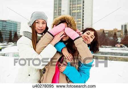 Stock Photography - Young woman covering eyes with friends. Fotosearch