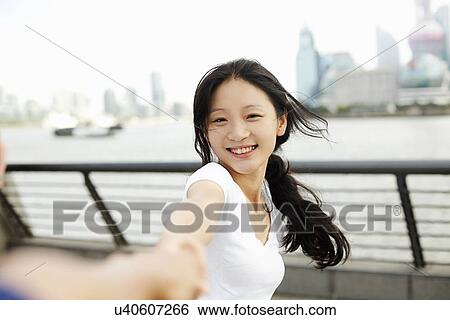 Stock Photograph - "Young woman dancing with boyfriend on the waterfront, The Bund, Shanghai, China". Fotosearch