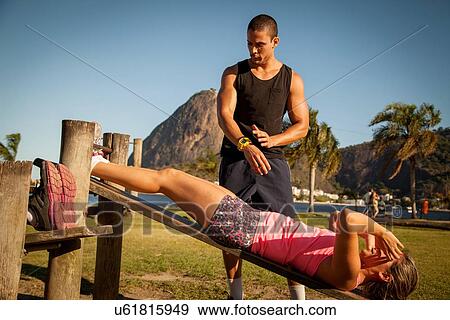 Young woman doing sit ups on wooden workbench in park View Large Photo Image Stock Photo - Young woman doing sit ups on wooden workbench in park. Fotosearch