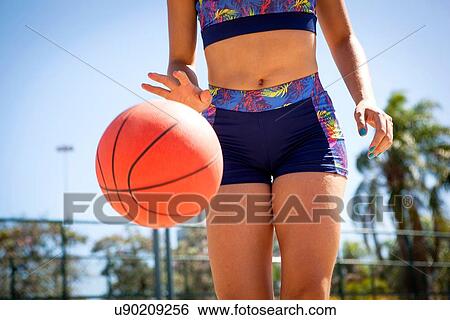 "Young woman dribbling basketball, mid section" View Large Photo Image Stock Photograph - "Young woman dribbling basketball, mid section". Fotosearch