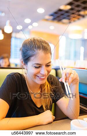 Stock Photo - "Young woman eating with chopsticks in restaurant, Manila, Philippines". Fotosearch
