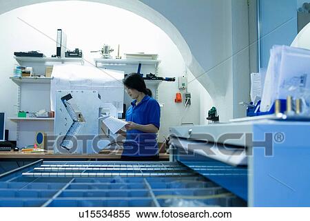 Young woman holding computer printout in industrial workshop View Large Photo Image Stock Photography - Young woman holding computer printout in industrial workshop. Fotosearch