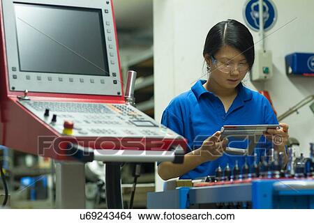 Picture - Young woman holding measuring equipment in industrial workshop. Fotosearch