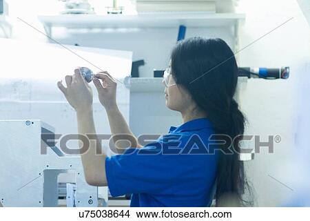 Young woman holding metal component in industrial workshop View Large Photo Image Picture - Young woman holding metal component in industrial workshop. Fotosearch