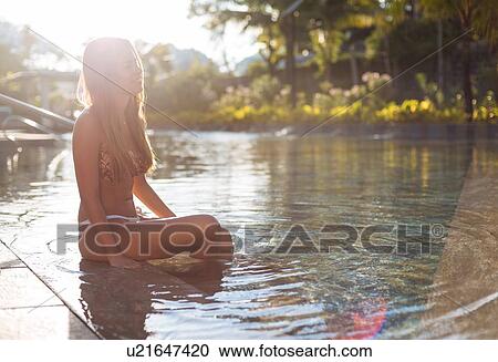 Stock Image - "Young woman in bikini sitting in swimming pool, Panay Island, Visayas, Philippines". Fotosearch