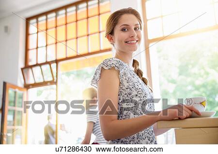 Stock Image - "Young woman in cafe, holding coffee cup". Fotosearch