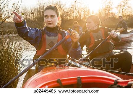 Stock Photography - "Young woman in canoe looking away, pointing". Fotosearch