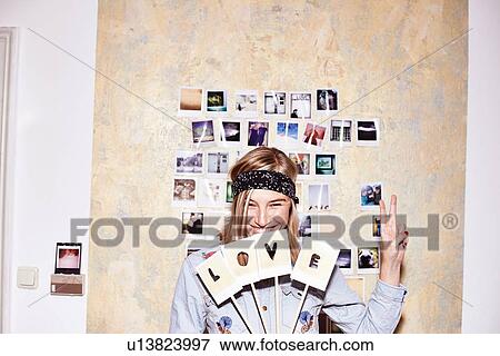 Young woman in front of photo wall holding up love and peace signs View Large Photo Image Stock Photo - Young woman in front of photo wall holding up love and peace signs. Fotosearch