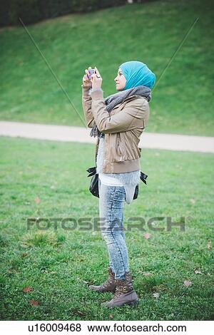 Young woman in park photographing on smartphone View Large Photo Image Stock Photo - Young woman in park photographing on smartphone. Fotosearch
