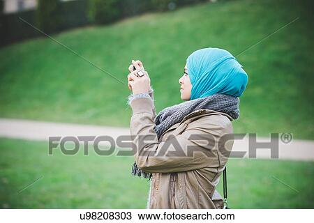 Young woman in park photographing with smartphone View Large Photo Image Stock Image - Young woman in park photographing with smartphone. Fotosearch