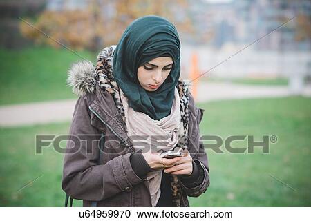 Young woman in park texting on smartphone View Large Photo Image Stock Image - Young woman in park texting on smartphone. Fotosearch