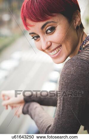 "Young woman leaning against balcony railings, smiling" View Large Photo Image Stock Image - "Young woman leaning against balcony railings, smiling". Fotosearch