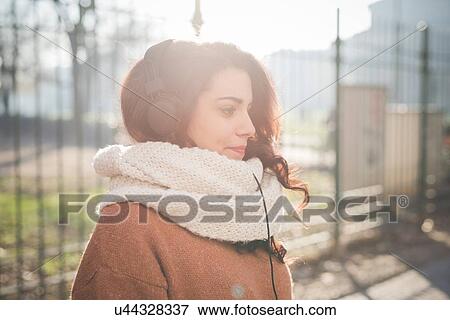 Young woman listening to headphones in park View Large Photo Image Stock Photo - Young woman listening to headphones in park. Fotosearch