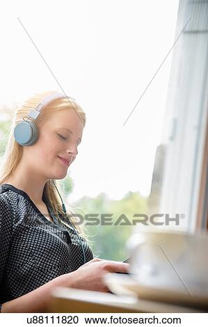Young woman listening to music with earphones View Large Photo Image Stock Image - Young woman listening to music with earphones. Fotosearch