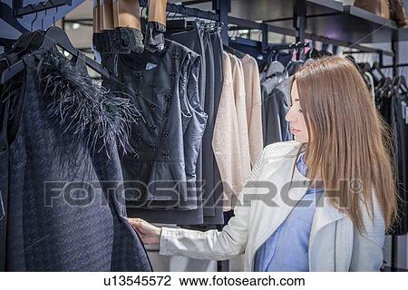 Young woman looking at dress in boutique View Large Photo Image Stock Image - Young woman looking at dress in boutique. Fotosearch