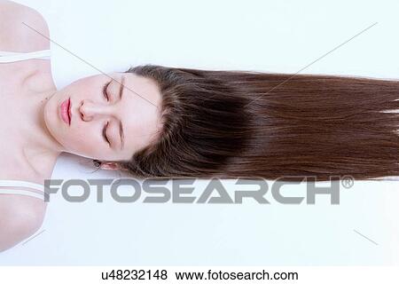 "Young woman lying down, hair stretched out behind her" View Large Photo Image Stock Photo - "Young woman lying down, hair stretched out behind her". Fotosearch