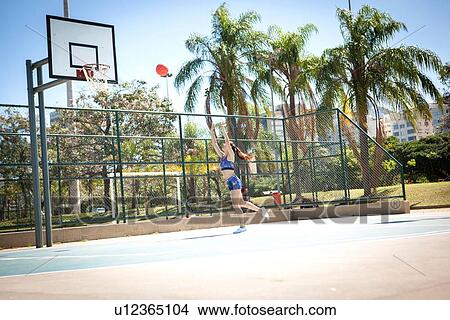 "Young woman on outdoor basketball court, throwing ball towards hoop" View Large Photo Image Picture - "Young woman on outdoor basketball court, throwing ball towards hoop". Fotosearch