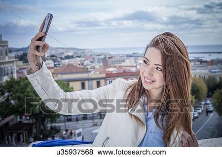 "Young woman on rooftop taking smartphone selfie, Cagliari, Sardinia, Italy" View Large Photo Image Stock Photo - "Young woman on rooftop taking smartphone selfie, Cagliari, Sardinia, Italy". Fotosearch
