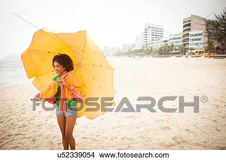 Picture - "Young woman posing with umbrella on beach, Rio de Janeiro, Brazil". Fotosearch