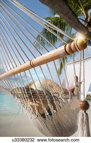 Stock Image - Young woman relaxing on a hammock on a tropical island. Fotosearch