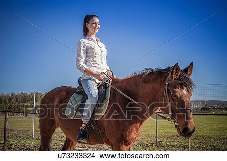 Picture - Young woman riding horse. Fotosearch