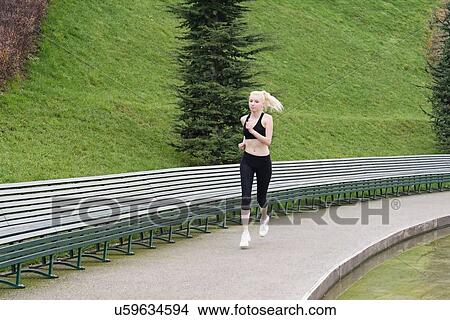 Picture - Young woman running beside lake. Fotosearch