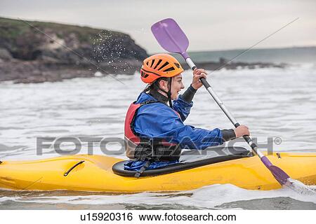 Stock Photograph - Young woman sea kayaking. Fotosearch