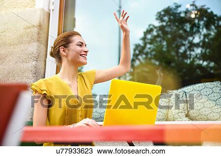 "Young woman signalling to waiter, using laptop outside cafe" View Large Photo Image Stock Image - "Young woman signalling to waiter, using laptop outside cafe". Fotosearch