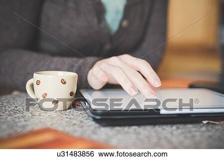 "Young woman sitting at table using digital tablet, focus on hands" View Large Photo Image Stock Photograph - "Young woman sitting at table using digital tablet, focus on hands". Fotosearch