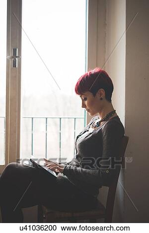 "Young woman sitting by window, using digital tablet" View Large Photo Image Stock Image - "Young woman sitting by window, using digital tablet". Fotosearch