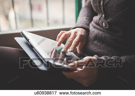 "Young woman sitting by window, using digital tablet, focus on hands" View Large Photo Image Stock Photo - "Young woman sitting by window, using digital tablet, focus on hands". Fotosearch