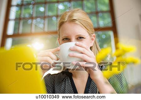 "Young woman sitting in cafe, drinking coffee, using laptop" View Large Photo Image Stock Photo - "Young woman sitting in cafe, drinking coffee, using laptop". Fotosearch