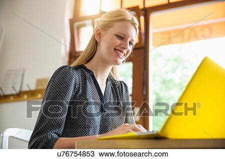 "Young woman sitting in cafe, using laptop, low angle view" View Large Photo Image Stock Image - "Young woman sitting in cafe, using laptop, low angle view". Fotosearch