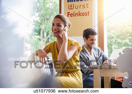Stock Photograph - "Young woman sitting in cafe, using mobile phone". Fotosearch