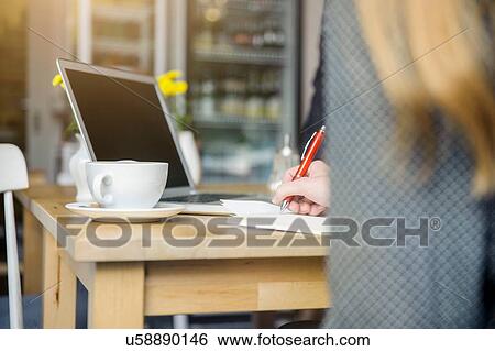 Stock Photograph - "Young woman sitting in cafe, using laptop, rear view". Fotosearch