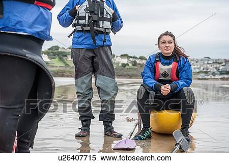 Stock Photography - Young woman sitting on kayak on beach. Fotosearch
