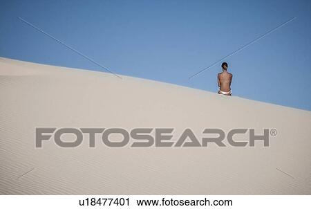 Young woman sitting on sand dune against clear blue sky View Large Photo Image Stock Image - Young woman sitting on sand dune against clear blue sky. Fotosearch