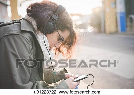 Young woman sitting on sidewalk reading smartphone texts View Large Photo Image Stock Image - Young woman sitting on sidewalk reading smartphone texts. Fotosearch