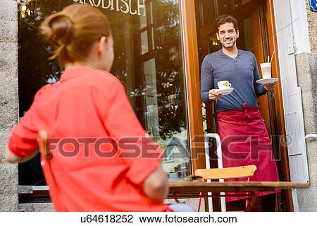 "Young woman sitting outside cafe, cafe worker bringing drinks out" View Large Photo Image Stock Image - "Young woman sitting outside cafe, cafe worker bringing drinks out". Fotosearch