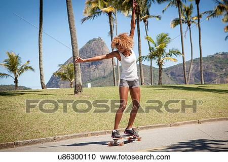 Young woman skateboarding along pavement View Large Photo Image Stock Image - Young woman skateboarding along pavement. Fotosearch